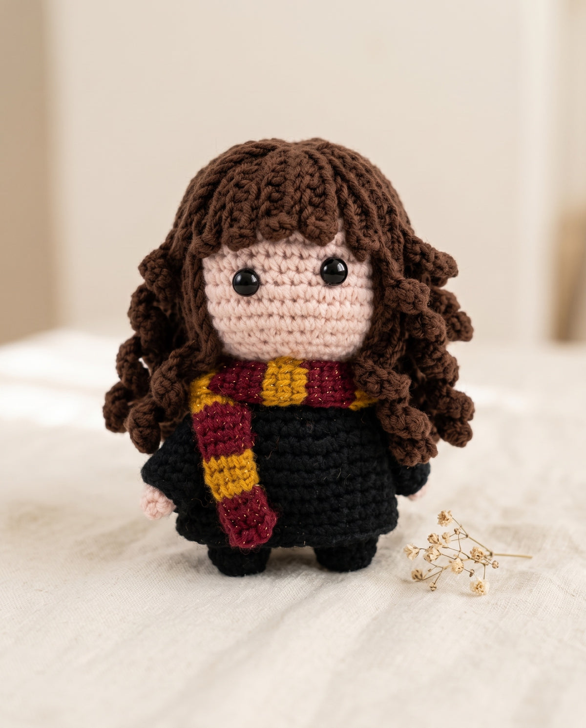 Hermione crochet toy with curly brown hair and red and gold scarf on white background
