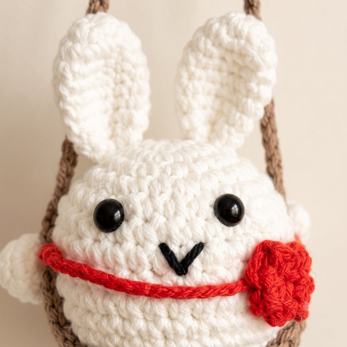 Close-up of crochet bunny with red crochet rose and black eyes