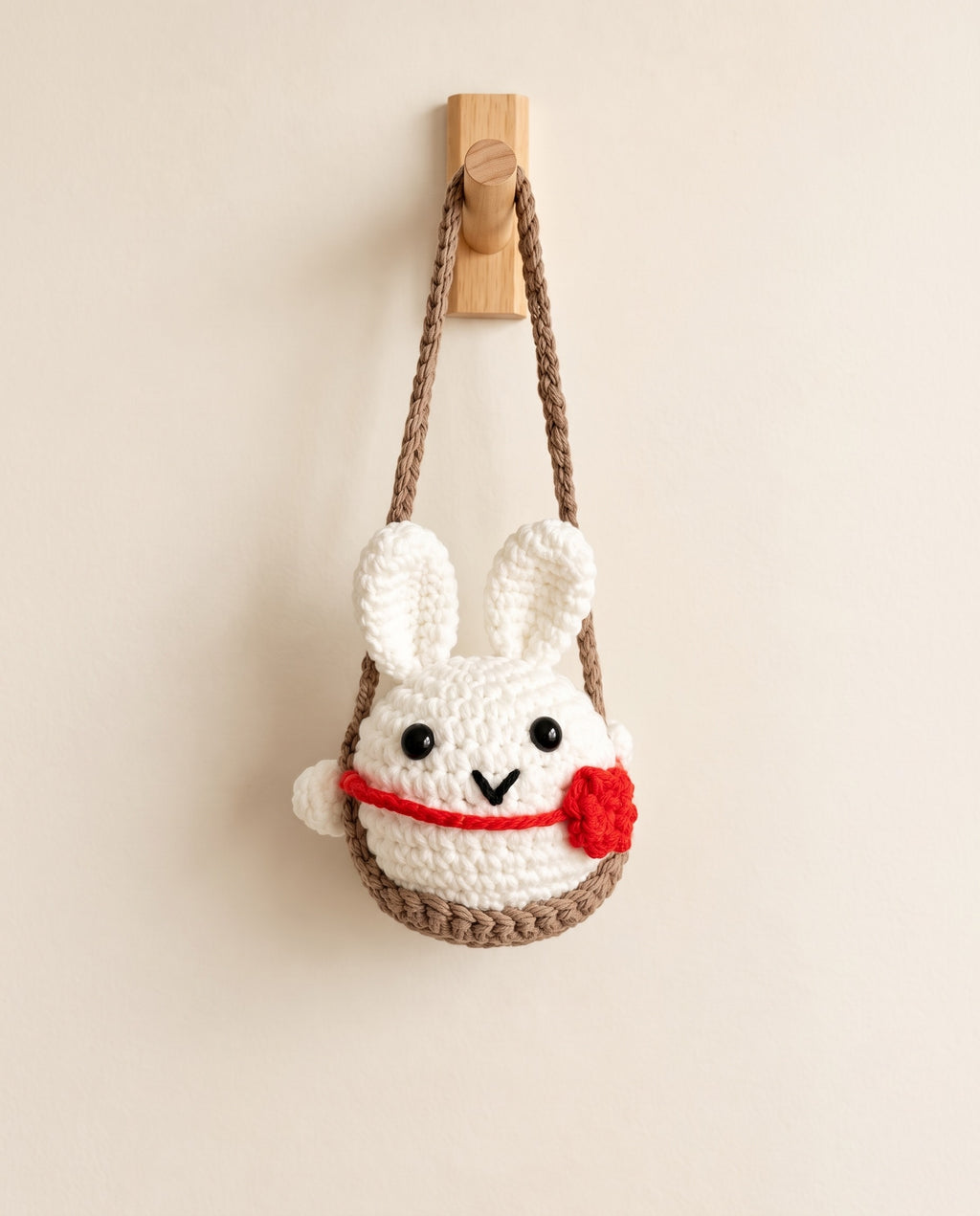 Handmade crochet bunny hanging on white background
