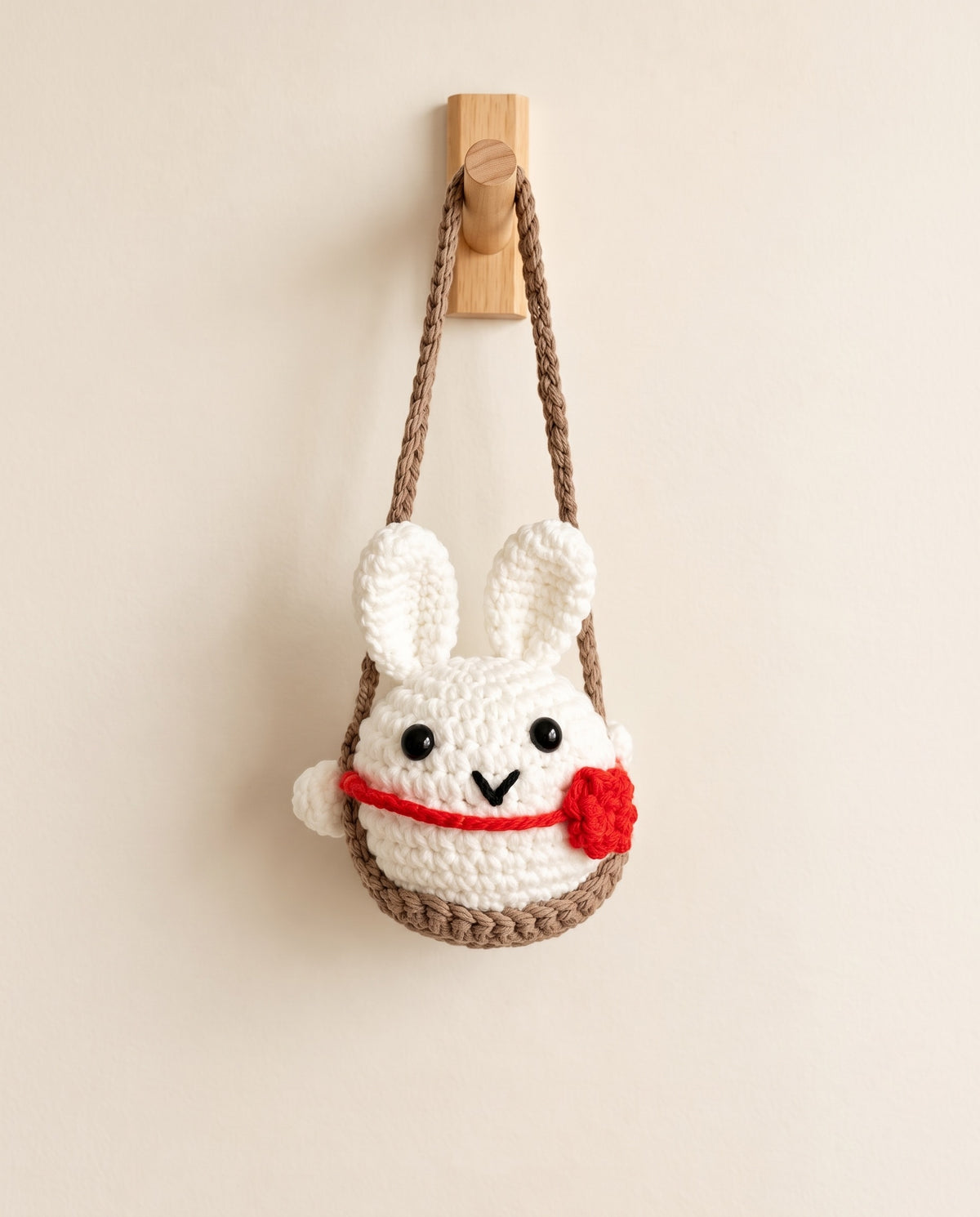 Handmade crochet bunny hanging on white background
